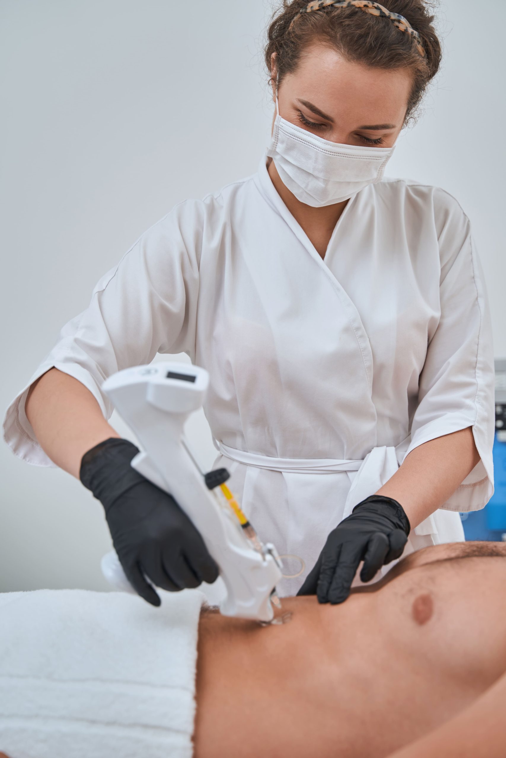 Profesional aplicando tratamiento corporal con mesogun en el abdomen de un paciente.
